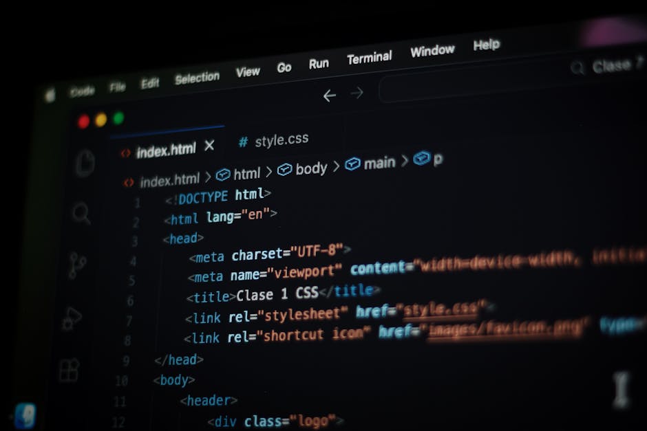 A close-up view of a person's hand wearing a black wristwatch, resting on a laptop keyboard with a visible screen displaying lines of code or programming language. The laptop is placed on a wooden sur